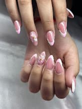Pink almond-shaped nails with white French tips and delicate floral accents on manicured hands.